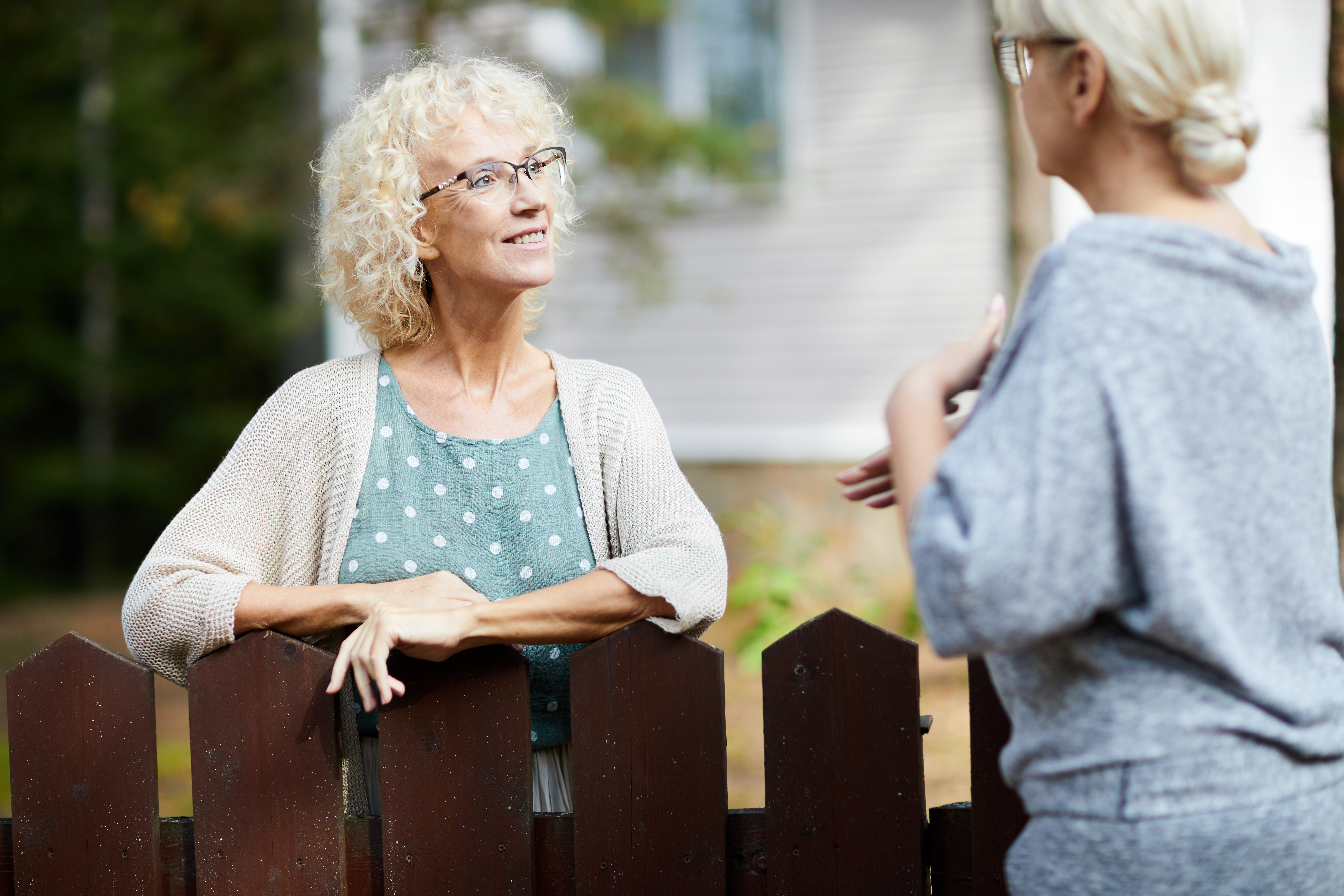 Two,Mature,Female,Neighbours,Talking,Through,Fence,About,Everyday,Life Photo By Lorraine Bramwell Associates: Two women discussing issues through the fence. Context: Mediation for neighbour and community disputes - is the best way forward